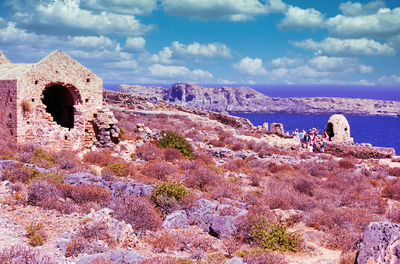 People on rock formations against sky