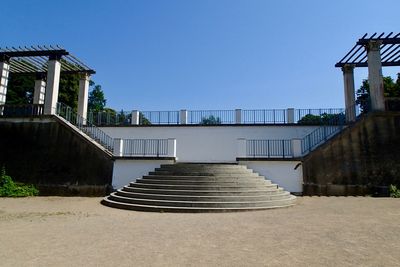 Low angle view of staircase by building against clear blue sky