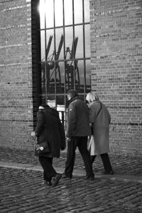 Rear view of people walking in front of wall