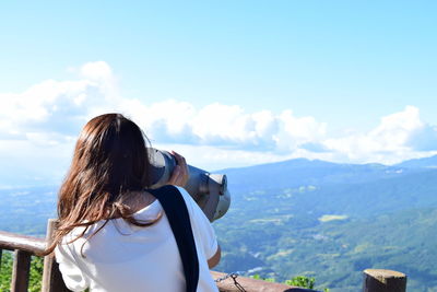 Rear view of woman looking at mountain through binocular