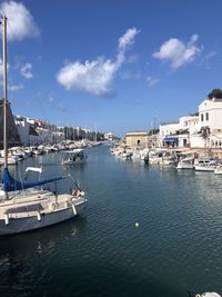 Boats in harbor in city against sky