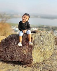 Portrait of boy sitting on rock at beach . model photoshoot