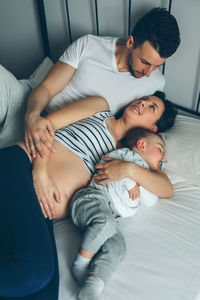 High angle view of pregnant woman with husband and son on bed at home