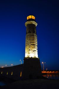 Low angle view of illuminated lighthouse against clear sky at night