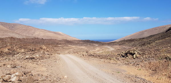 Dirt road on desert against sky