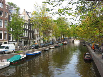 Boats moored in canal amidst buildings in city