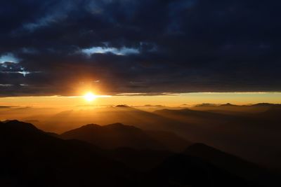 Scenic view of silhouette landscape against sky during sunset under dramatic clouds , blue hour