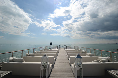 Chairs by sea against sky