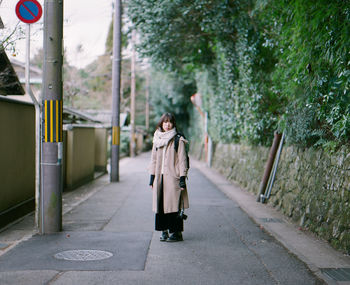 Woman walking on road along trees