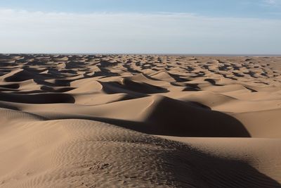 Sand dunes in desert against sky