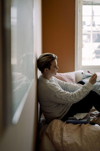 Depressed young lesbian woman with pregnancy test results sitting on bed at home