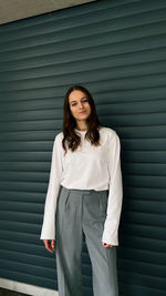 Portrait of a beautiful young woman standing against wall