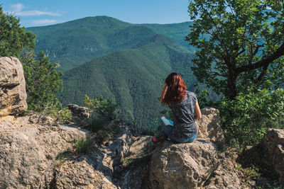 Man sitting on rock looking at mountains