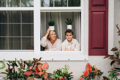 Portrait of woman and girl looking through window into the garden 