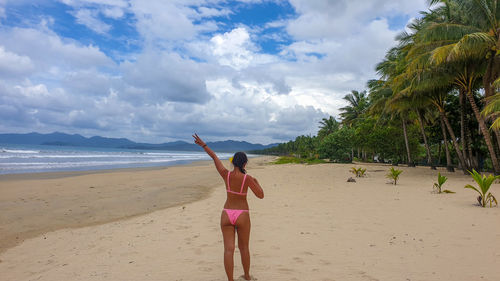 Rear view of woman on beach against sky