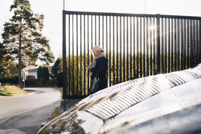 Side view of woman standing by car