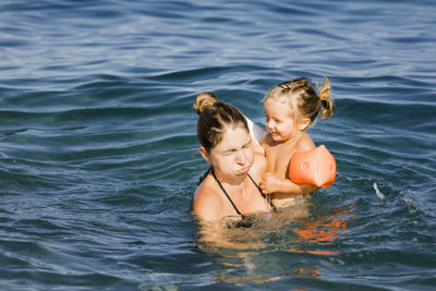 Woman and daughter swimming in sea