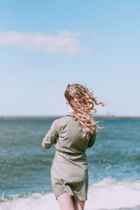 Rear view of man on beach against sky