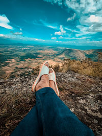 Low section of man standing on mountain against sky