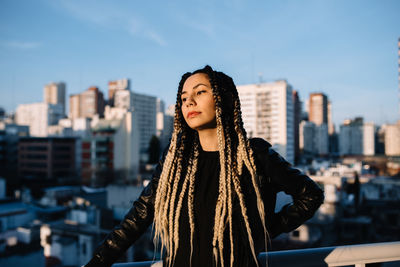 Young woman standing in city against sky during winter