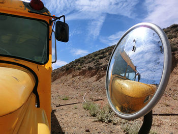 Close-up of side-view mirror against sky