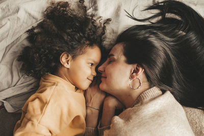 Smiling mother with daughter lying on bed at home