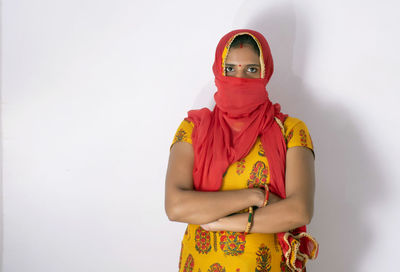 Portrait of woman wearing flu mask standing against white background