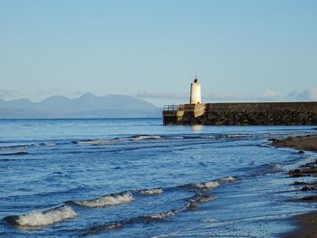 Lighthouse by sea against sky