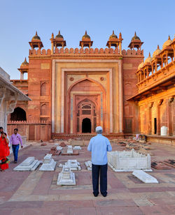 Rear view of man walking in temple against sky