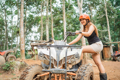 Side view of young woman standing in forest