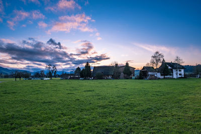 Houses on field against sky during sunset