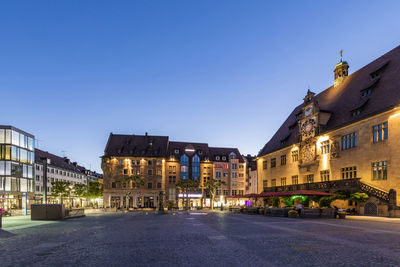 Street amidst buildings against clear blue sky at dusk