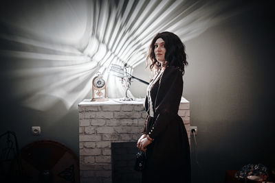 Portrait of woman standing against wall at home