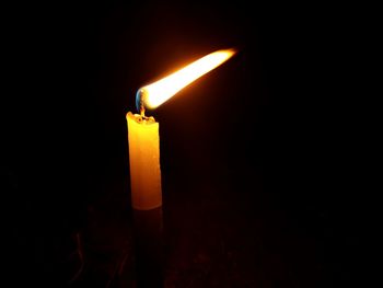 Close-up of lit candle in darkroom