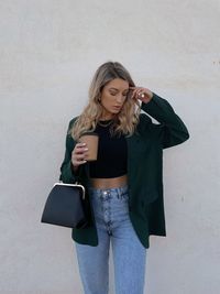 Young woman standing against wall