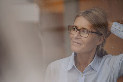 Businesswoman behind rainy windowpane looking away