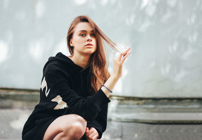 Portrait of beautiful young woman crouching outdoors