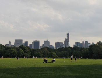 People at public park against sky in city