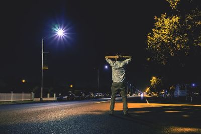 Man standing on illuminated street at night