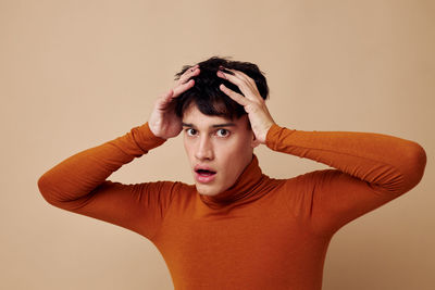 Portrait of young woman standing against yellow background