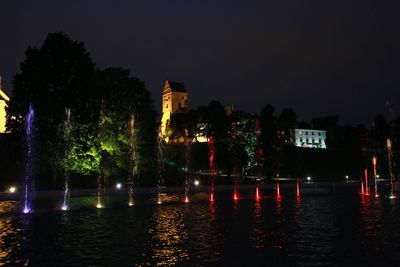 Illuminated city by trees at night