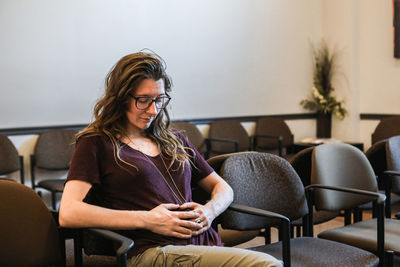 Young woman using phone while sitting on chair