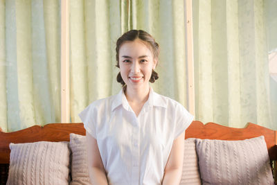 Portrait of smiling young woman sitting on sofa at home