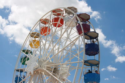 Low angle view of ferris wheel against cloudy sky