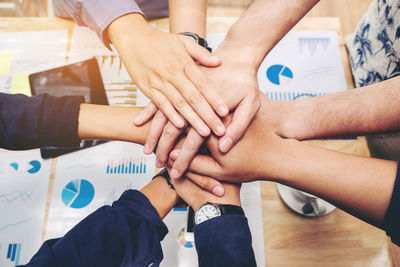 Cropped hands of business people huddling over table in office