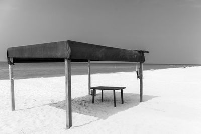 Chair on table by sea against sky