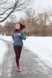 Full length of woman jogging on road during winter