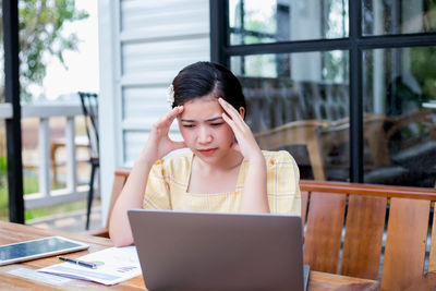 Young woman using mobile phone while sitting on table