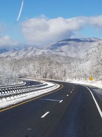 Scenic view of road by mountains against sky