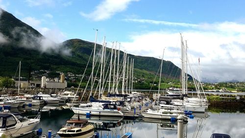 Boats moored at harbor against sky